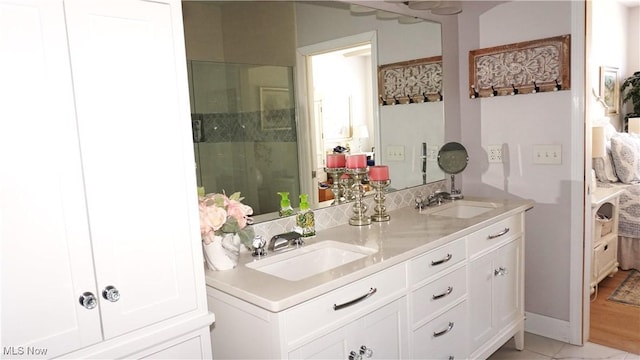 bathroom with double vanity, a stall shower, and a sink