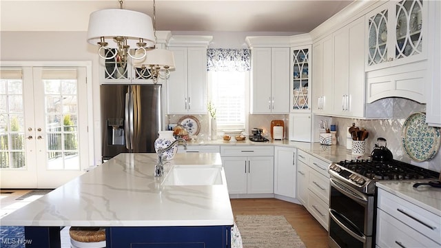 kitchen with a kitchen island, a sink, stainless steel appliances, french doors, and tasteful backsplash