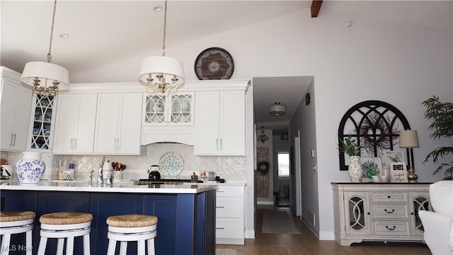 kitchen with a breakfast bar, lofted ceiling with beams, dark wood finished floors, glass insert cabinets, and backsplash