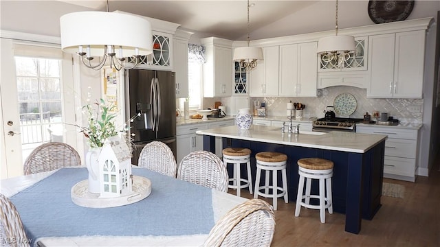 kitchen featuring backsplash, an island with sink, lofted ceiling, light countertops, and stainless steel appliances