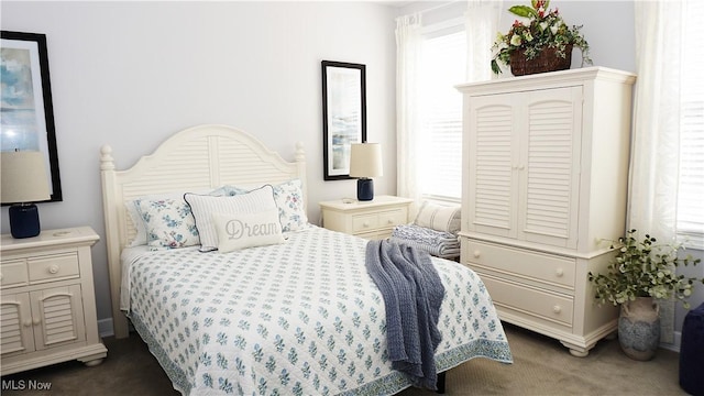 bedroom featuring dark carpet and baseboards