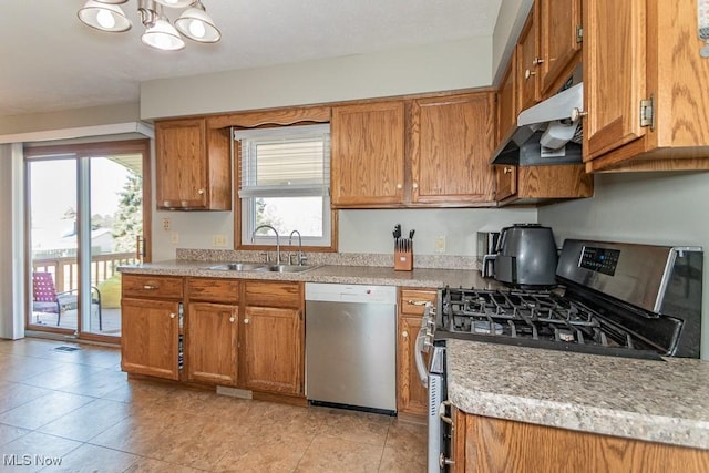 kitchen with a notable chandelier, under cabinet range hood, a sink, appliances with stainless steel finishes, and brown cabinetry