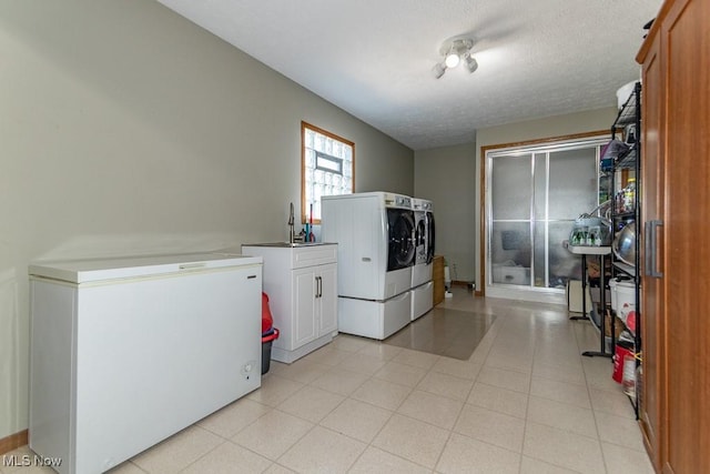 laundry area featuring cabinet space, washer and dryer, a textured ceiling, and a sink