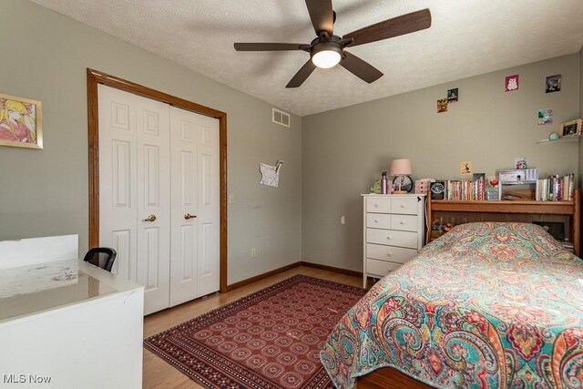 bedroom featuring visible vents, baseboards, a closet, a textured ceiling, and a ceiling fan