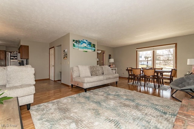 living room featuring baseboards, a textured ceiling, and wood finished floors