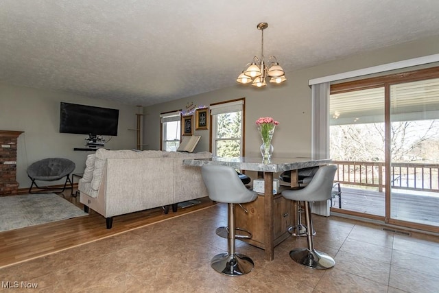 dining room featuring an inviting chandelier, wood finished floors, visible vents, and a textured ceiling