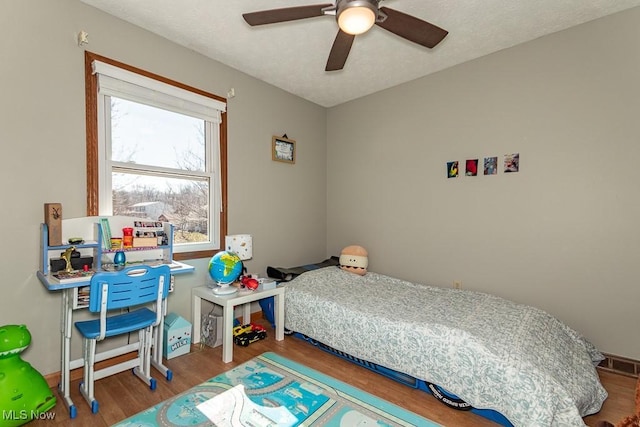 bedroom with ceiling fan, visible vents, a textured ceiling, and wood finished floors