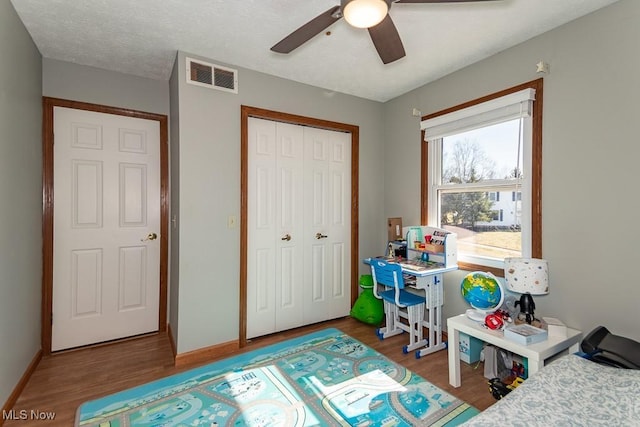 bedroom featuring visible vents, wood finished floors, a closet, baseboards, and ceiling fan