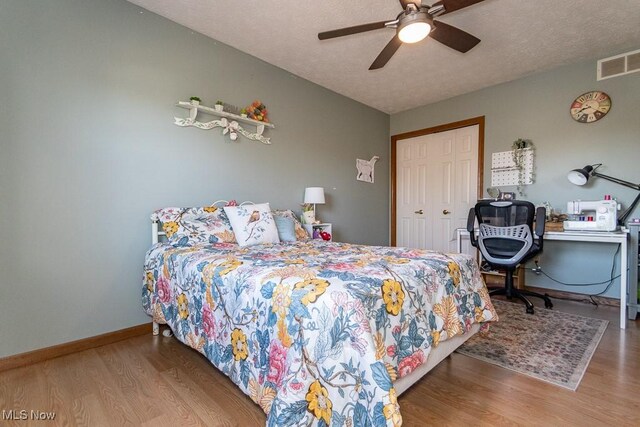 bedroom with a closet, visible vents, baseboards, and wood finished floors