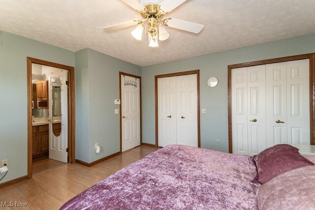 bedroom with baseboards, light wood-type flooring, two closets, and a textured ceiling