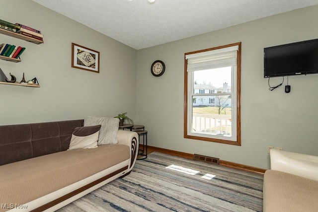 sitting room featuring visible vents, a textured ceiling, baseboards, and wood finished floors