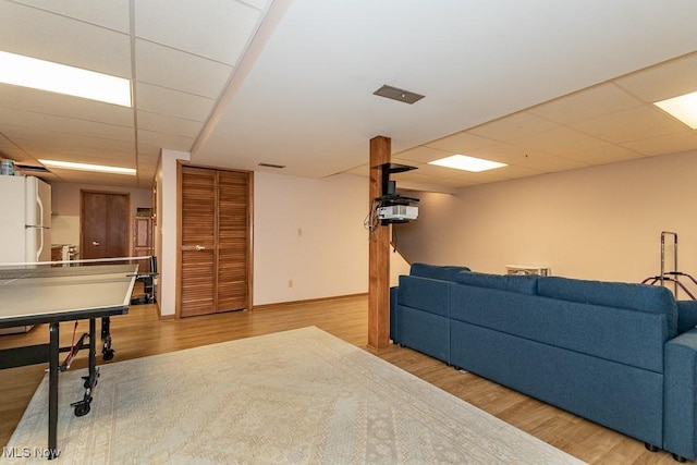 living area with visible vents, a paneled ceiling, baseboards, and wood finished floors