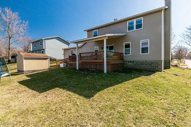 back of house featuring a wooden deck, a lawn, central AC unit, an outbuilding, and a storage unit