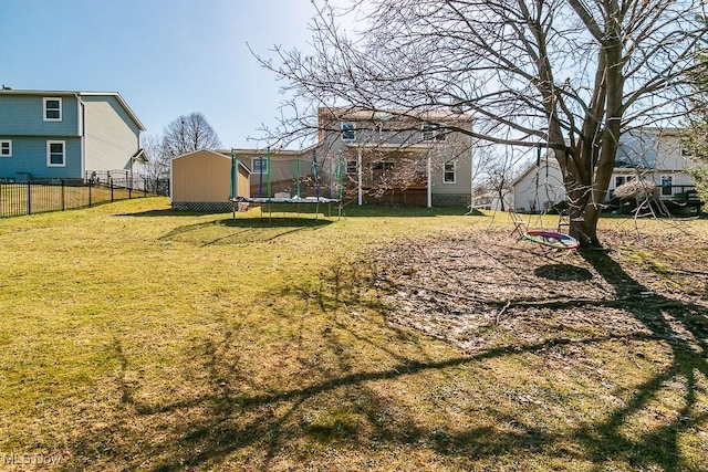 view of yard featuring a storage unit, an outdoor structure, a trampoline, and fence