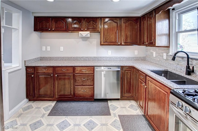 kitchen with a sink, baseboards, appliances with stainless steel finishes, and light countertops