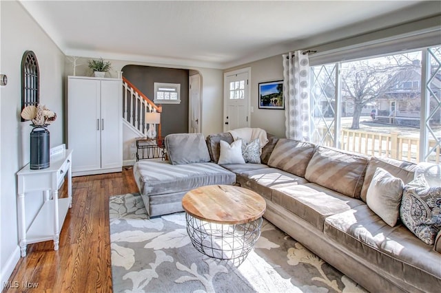 living area featuring stairway, plenty of natural light, wood finished floors, and arched walkways