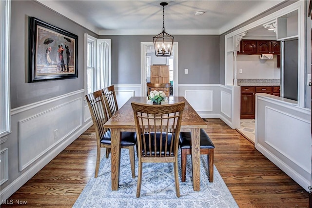 dining room featuring an inviting chandelier, dark wood-style flooring, and wainscoting