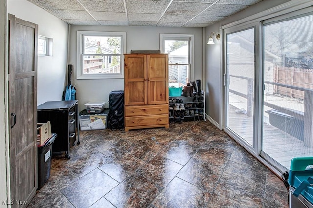 interior space featuring a drop ceiling, baseboards, and stone finish floor