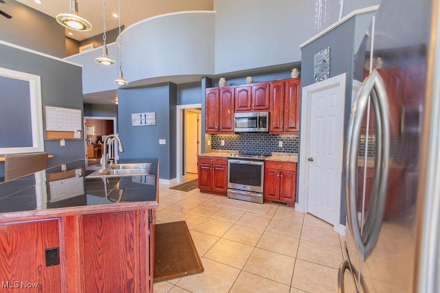 kitchen with a high ceiling, light tile patterned flooring, a sink, stainless steel appliances, and tasteful backsplash