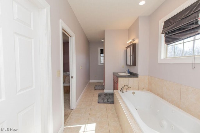 bathroom featuring tile patterned floors, a jetted tub, vanity, and baseboards