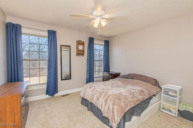 carpeted bedroom with visible vents, baseboards, and a ceiling fan