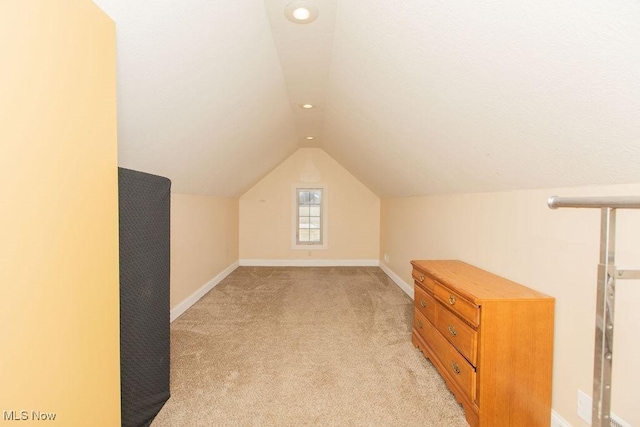 bonus room featuring vaulted ceiling, light colored carpet, and baseboards