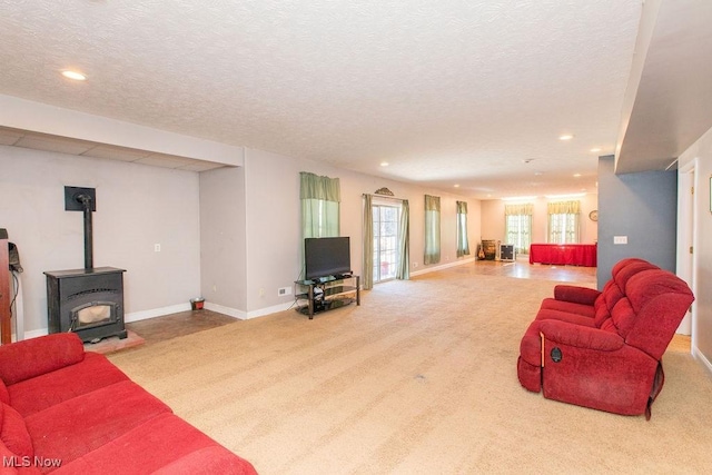 carpeted living room with recessed lighting, baseboards, a textured ceiling, and a wood stove