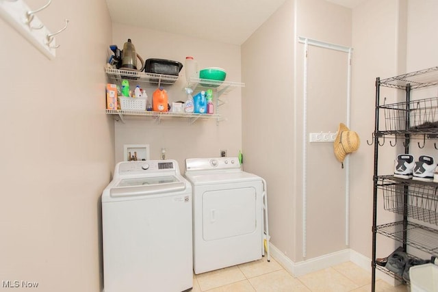 laundry room featuring washer and clothes dryer, laundry area, baseboards, and light tile patterned flooring