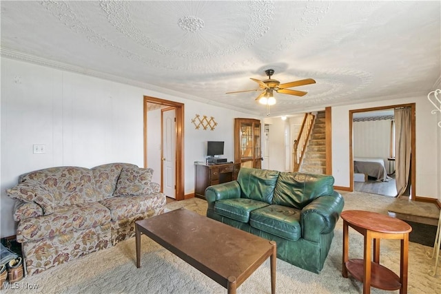 living area featuring ceiling fan, stairway, baseboards, and a textured ceiling