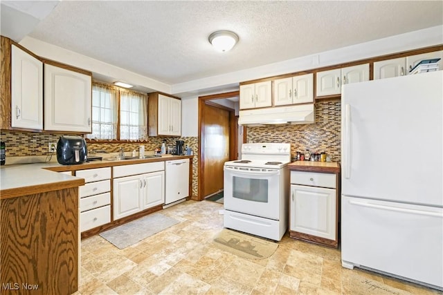 kitchen with white appliances, a sink, under cabinet range hood, white cabinetry, and backsplash