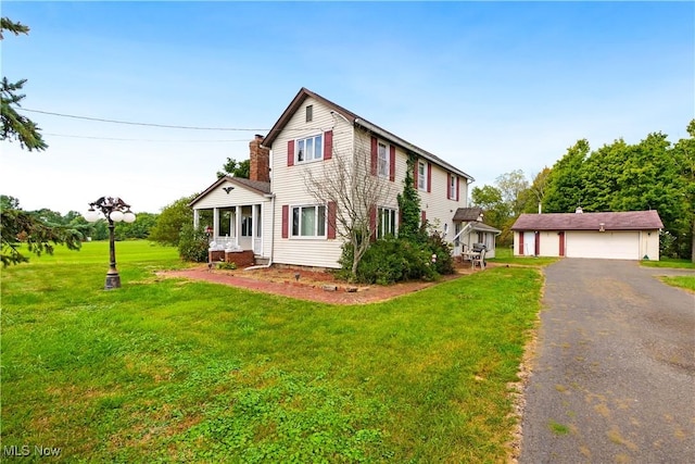 view of front facade featuring an outbuilding, a chimney, a detached garage, and a front lawn