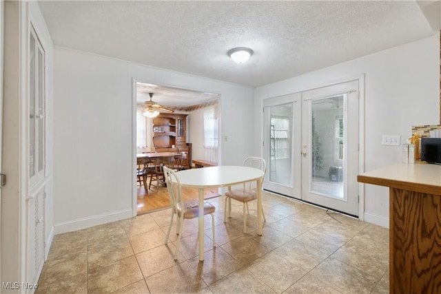 dining room featuring a ceiling fan, french doors, baseboards, and a textured ceiling