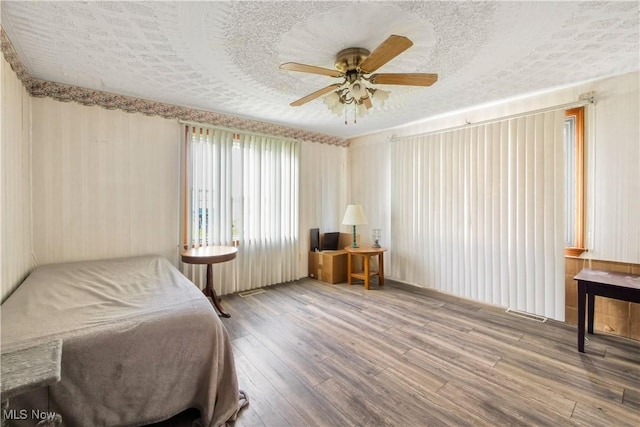 bedroom with ceiling fan, wood finished floors, visible vents, and a textured ceiling