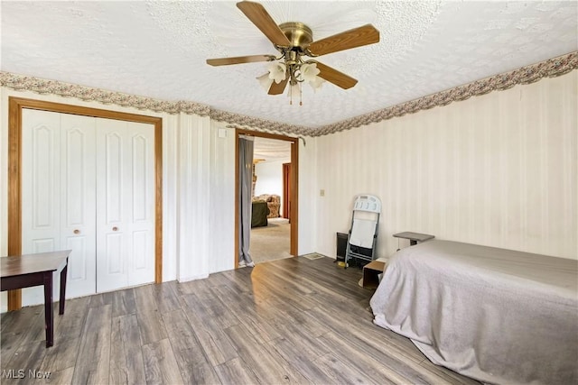 bedroom with ceiling fan, wood finished floors, a closet, and a textured ceiling