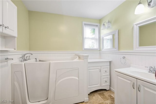 full bathroom with a wainscoted wall and vanity