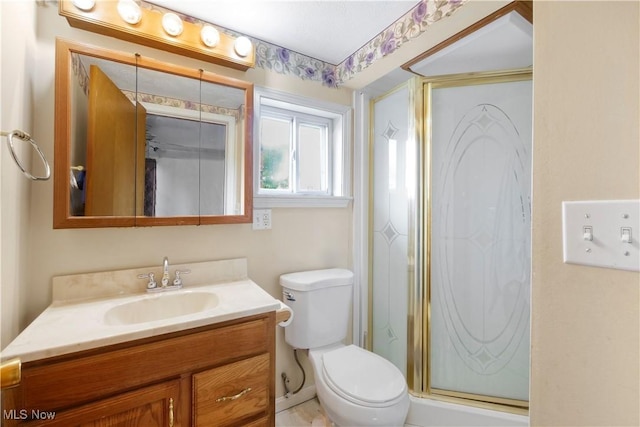 full bathroom featuring a stall shower, toilet, and vanity