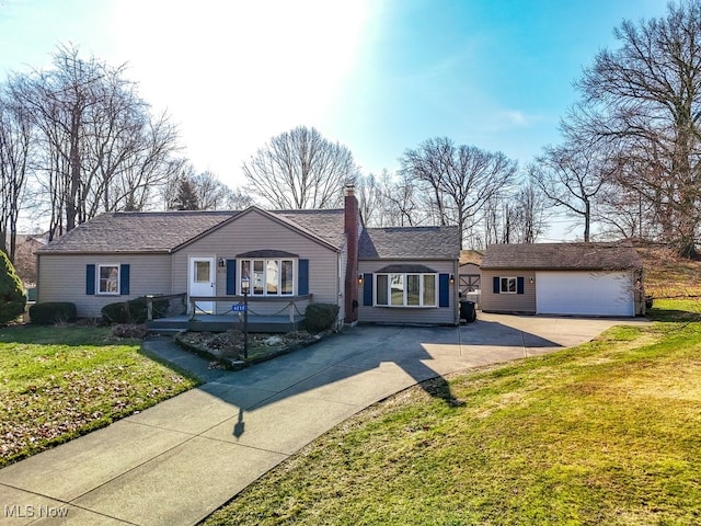 single story home with an outbuilding, driveway, a garage, and a front yard