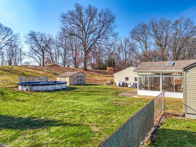 view of yard featuring a covered pool, fence, a sunroom, an outbuilding, and a storage unit