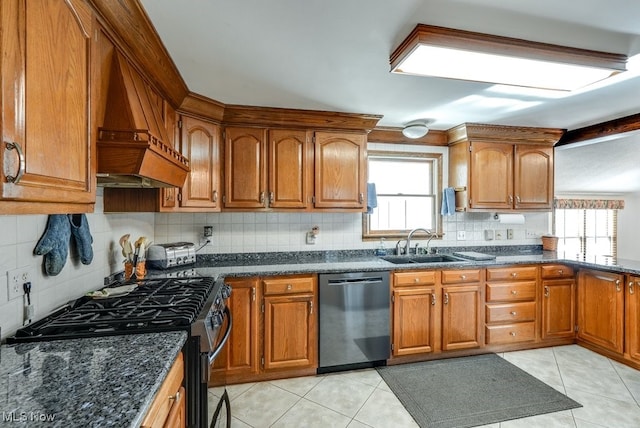 kitchen with a healthy amount of sunlight, premium range hood, brown cabinets, stainless steel appliances, and a sink