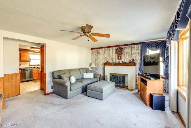 living room with light carpet, a fireplace, and a ceiling fan