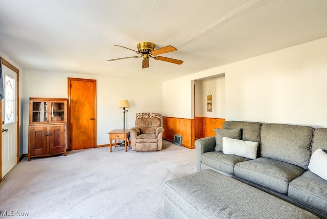 living room with visible vents, light carpet, a wainscoted wall, and a ceiling fan