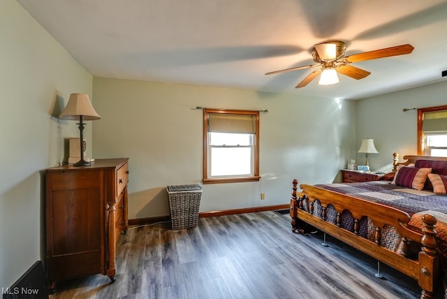 bedroom with multiple windows, dark wood-type flooring, and baseboards