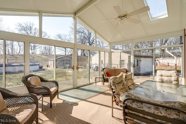 sunroom / solarium featuring lofted ceiling with skylight, a healthy amount of sunlight, and ceiling fan