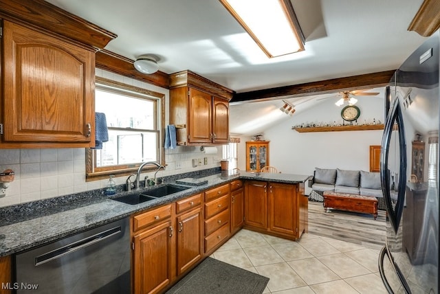 kitchen featuring tasteful backsplash, vaulted ceiling with beams, dishwashing machine, freestanding refrigerator, and a sink