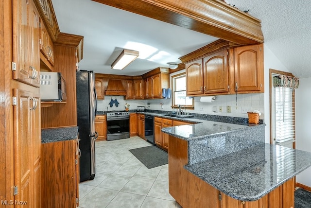 kitchen with premium range hood, appliances with stainless steel finishes, a peninsula, brown cabinetry, and a sink