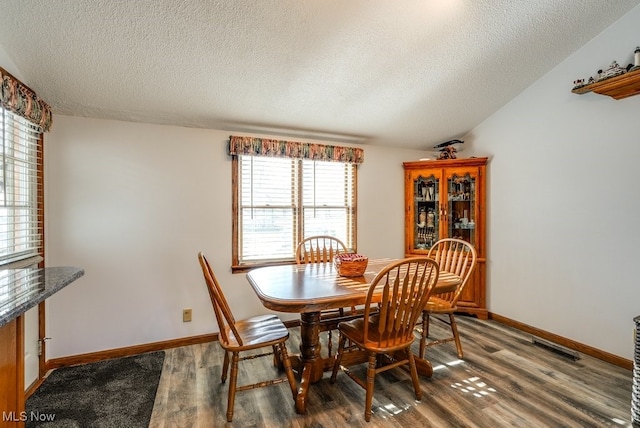 dining room featuring vaulted ceiling, baseboards, and wood finished floors