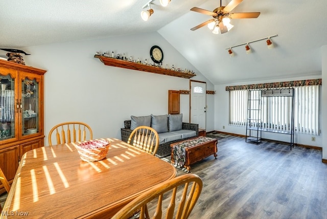 dining space with track lighting, a ceiling fan, wood finished floors, baseboards, and vaulted ceiling