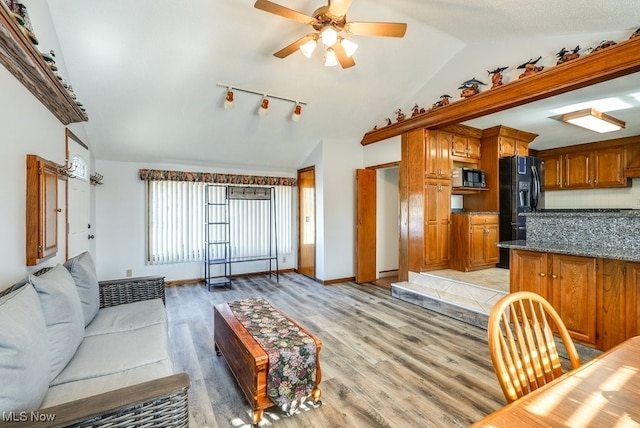 living area featuring vaulted ceiling, light wood-style flooring, baseboards, and ceiling fan