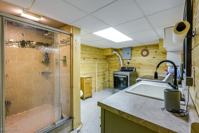 full bath with washer / clothes dryer, vanity, wood walls, and a shower stall