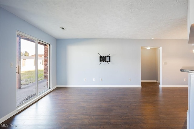 unfurnished room featuring visible vents, a textured ceiling, baseboards, and dark wood-style flooring